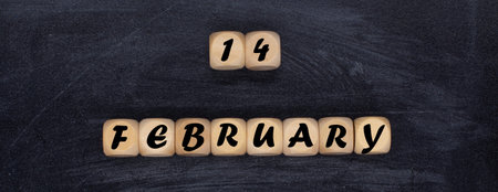 Message 14 February in wooden blocks on a black background. Valentine's Day