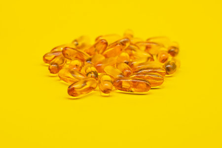 Omega 3 capsules lying on yellow background. Fish oil in pills. Health support and treatment. Biologically active additivesの写真素材