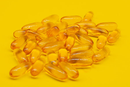 Omega 3 capsules lying on yellow background. Fish oil in pills. Health support and treatment....