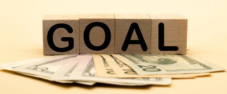 the word goal on wooden cubes and American dollars. Business concept