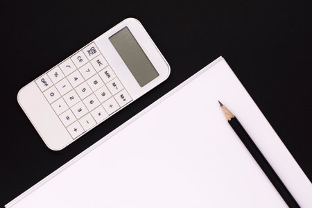 white calculator on black background, paper and pencils. Office desk. Business conceptの写真素材