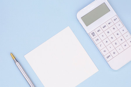 white calculator and note paper on blue background for your textの写真素材