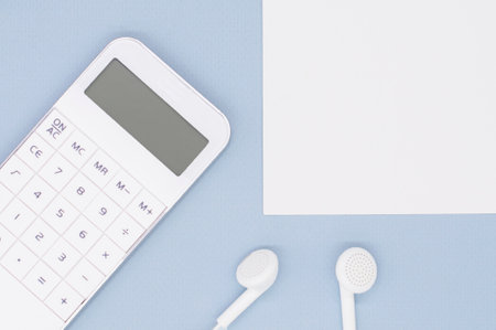 white calculator, headphones and note paper on blue background for your textの写真素材