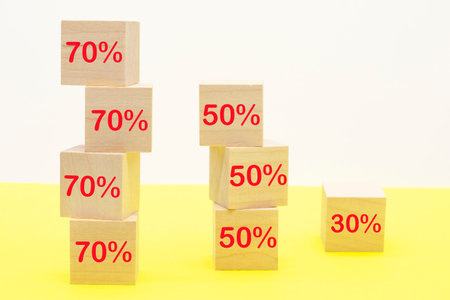 Red percent sign on wooden cubes against yellow background. Concept of sale and discount.