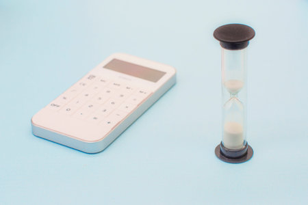 hourglass and white calculator. The concept of time for action. Concept of time