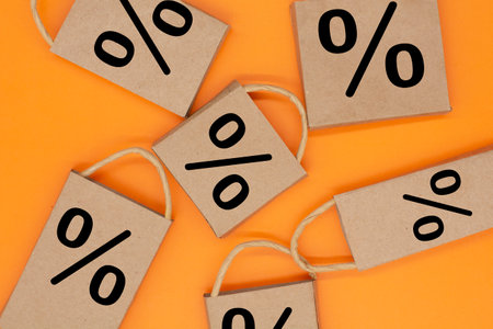 Percentage sign on the craft package on a orange background. creative idea for online shopping, sale, supermarket, discount promotion and black friday concept. Copy space for textの写真素材