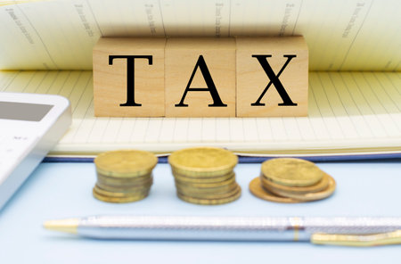 word tax on wooden cubes, coins, calculator and notepad. Business and tax concept. Pay taxの写真素材