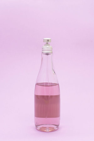 a glass bottle of body spray on a pink background. Spa