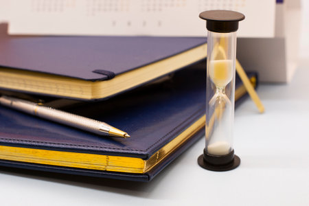 blue leather notebooks, hourglass and a pen. Preparing for a business meeting. Business conceptの写真素材