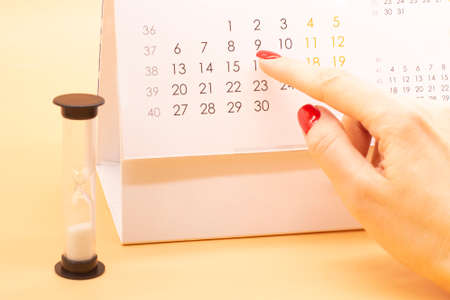 a woman's hand points to the calendar. Business planning. Time to taxesの写真素材
