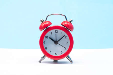 red round analog alarm clock isolated on blue background. time 10:10.の写真素材