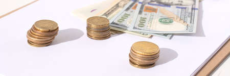 stacks of coins and 100 dollars on a white backgroundの写真素材