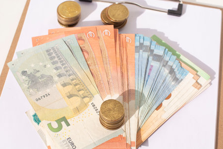 A calculator, stacks of coins and euro banknotes on a white background
