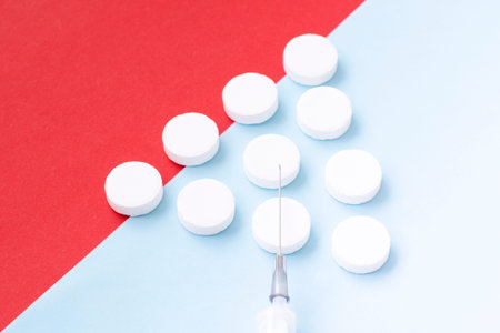 white yellow tablets and a syringe on a multicolored background