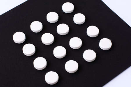 Round white medical pills arranged in square order on a black background. Pill splitting.の写真素材