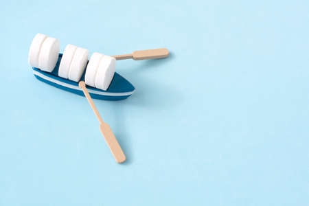 mini boat carrying pills on yellow background. Transportation and delivery of medicinesの写真素材