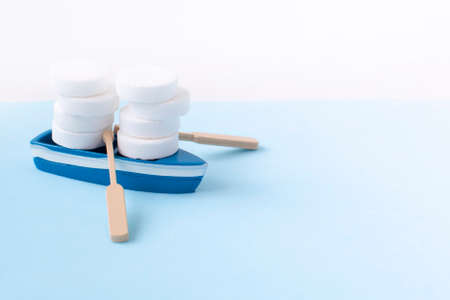 mini boat carrying pills on yellow background. Transportation and delivery of medicinesの写真素材
