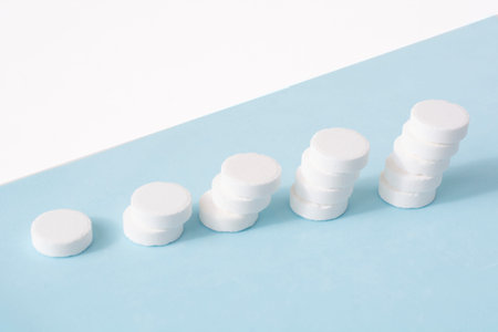 A stack of pills on a blue background. Growth graph made of stacked white pills - growing market and...