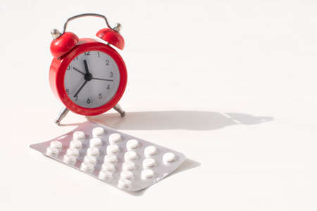 red alarm clock and pills. Time reminder for taking pills.Medicine in hospital.の写真素材