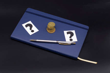 blue diary, question mark and pen on a black background. Planning and business conceptの写真素材