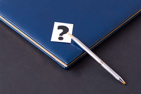 blue diary, question mark and pen on a black background. Planning and business conceptの写真素材