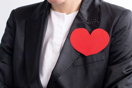 A businesswoman in a black suit with a red heart. The concept of charity and kindnessの写真素材