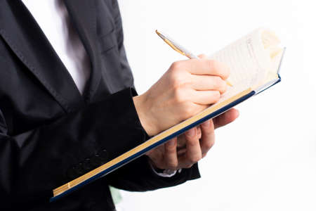 A businesswoman in a suit writing appointment on agendaの写真素材
