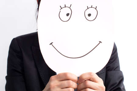 A businesswoman holds a smiling mask in her hands. The concept of positivityの写真素材
