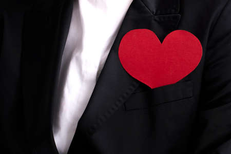 A businesswoman in a black suit with a red heart. The concept of charity and kindnessの写真素材