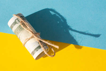 Twisted bundle 100 dollar bills on a yellow and blue background. Business conceptの写真素材