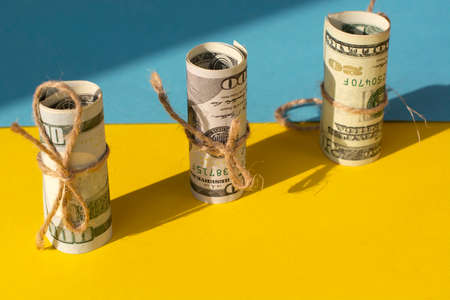 Twisted bundle 100 dollar bills on a yellow background. Business conceptの写真素材
