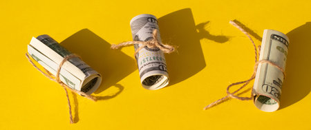Twisted bundle 100 dollar bills on a yellow and blue background. Business conceptの写真素材