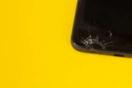 broken black mobile phone, screen crack on yellow backgroundの写真素材