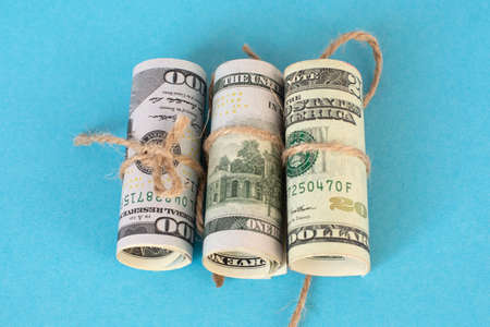 Twisted bundle 100 dollar bills on a blue background. Business conceptの写真素材