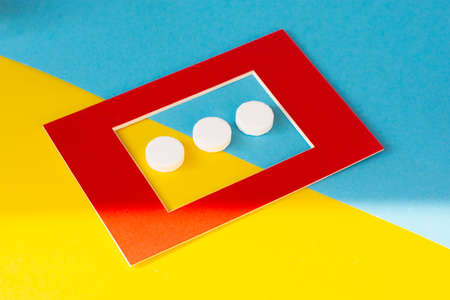 Macro shot of three white tablets in a red frame. Antacids pills for relief stomachache from excess gastric acid. Stress induce gastric ulcer treatment concept.の写真素材