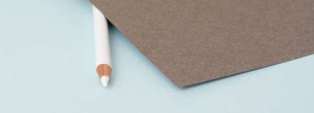 A white pencil on a blue background and gray paper on topの写真素材