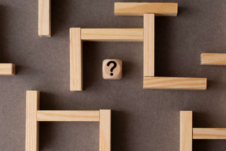 Maze or labyrinth made with wooden blocks with a wooden cube with question mark in the middle. Business strategy, problem solving, challenge or obstacle concept.の写真素材