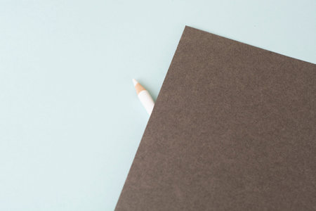 A white pencil on a blue background and gray paper on top