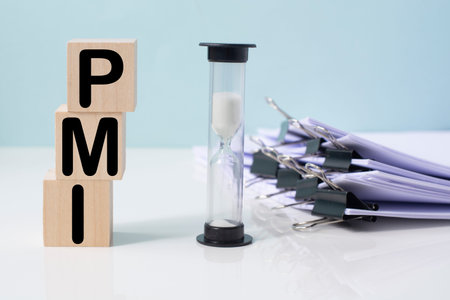 A hourglass next to wooden blocks with the text PMI. PMI - Purchasing Managers Index