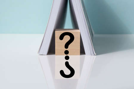 a question mark on a wooden cube between the pages of notepad. FAQ frequency asked questions, Answer and Brainstorming Conceptsの写真素材