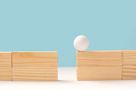 business concept image of education and challenge. Wooden ball on high wall and needs to be passed to the other side over a gap. Problem solving and decision making.の写真素材