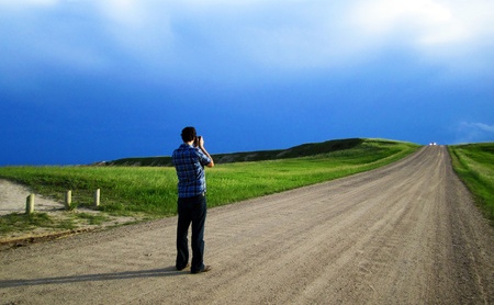 Lone man taking a photo in the road, Badlands National Park, South Dakotaの写真素材