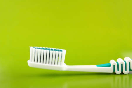 White-green tooth-brush close on a green backgroundの写真素材