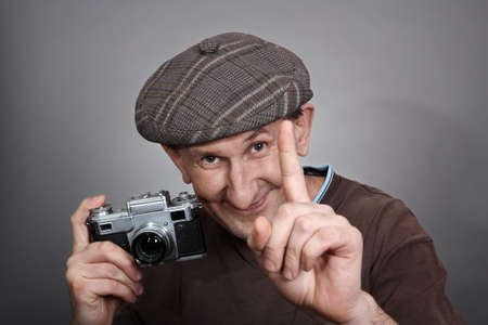 Photographer with an old retro camera, smiling. Studio shotの写真素材