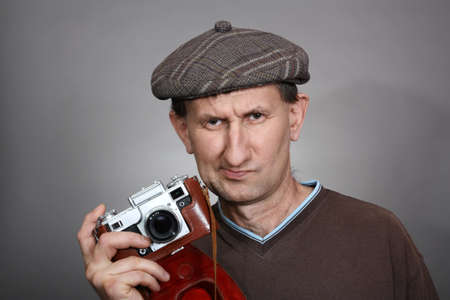Photographer with an old retro camera, on a gray background. Studio shotの写真素材