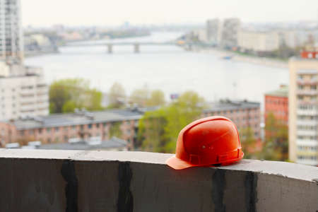 Construction. Construction helmet on the window of an unfinished house on the background of the cityの写真素材