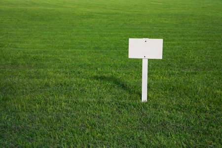 White, clean signboard on a green lawnの写真素材
