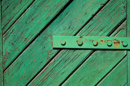A fragment of an old, painted, wooden door with hingesの写真素材