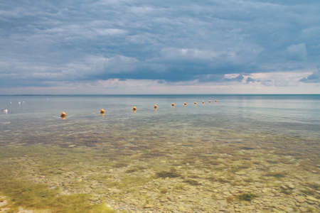 Tranquility seascape, stones at the bottom of the calm sea against the cloudy skyの写真素材