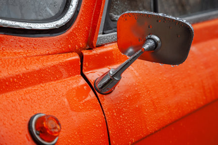 Rear view mirror of an orange retro car in the rain closeupの写真素材
